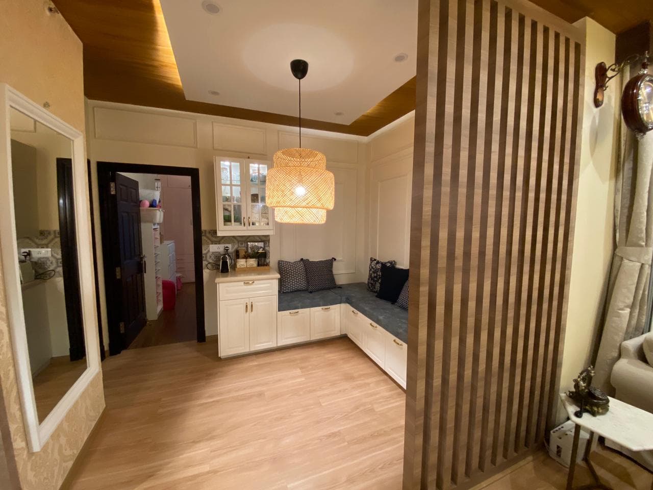A cozy window seat with rattan pendant light and wood-slat partition